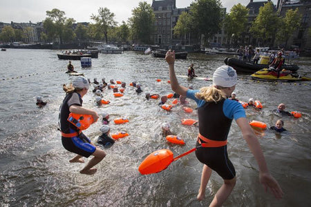 Enfants sautant dans l'eau avec des bouées 360swim lors de l'Amsterdam City Swim