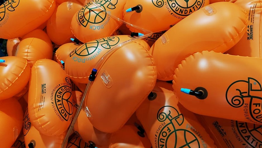 Montón de boyas naranjas 360swim™ con logotipos personalizados de eventos y patrocinadores.