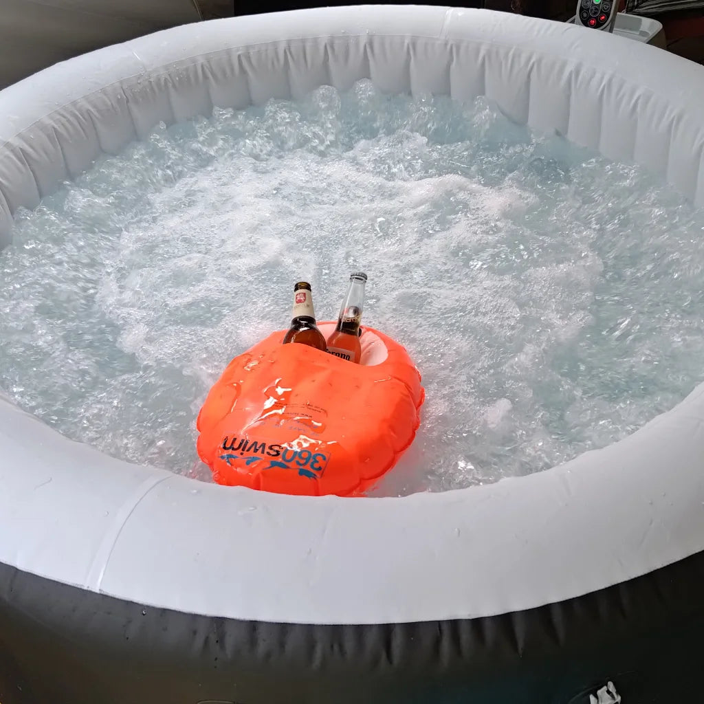Inflatable hot tub with a floating orange buoy holding two bottles of beer, surrounded by bubbling water.