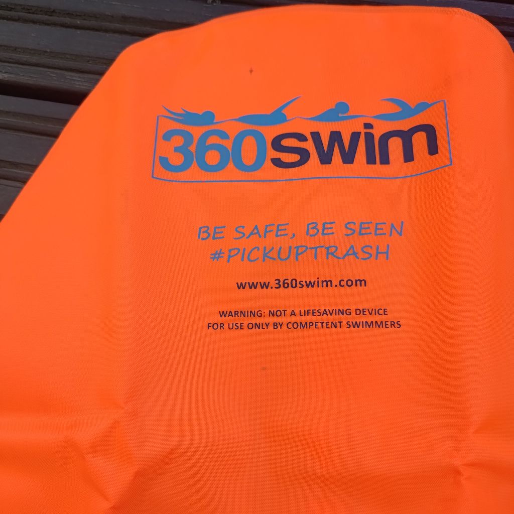Orangefarbener Schwimmfloat mit 360swim-Branding und Sicherheitsaufschrift auf Holzoberfläche